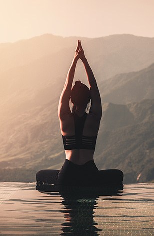 Back of a woman practising yoga in front of mountains