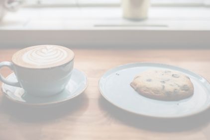 Photo d'une tasse de tchai latte à côté d'une assiette avec un cookie chocolat bilva