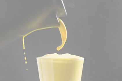 Saucepan pouring golden milk into a glass