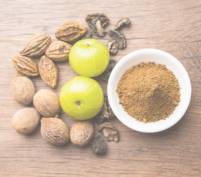 Les 3 baies du triphala à côté d'un bol de poudre